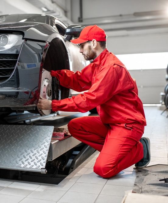 mecanico con mono rojo cambia rueda de vehiculo negro